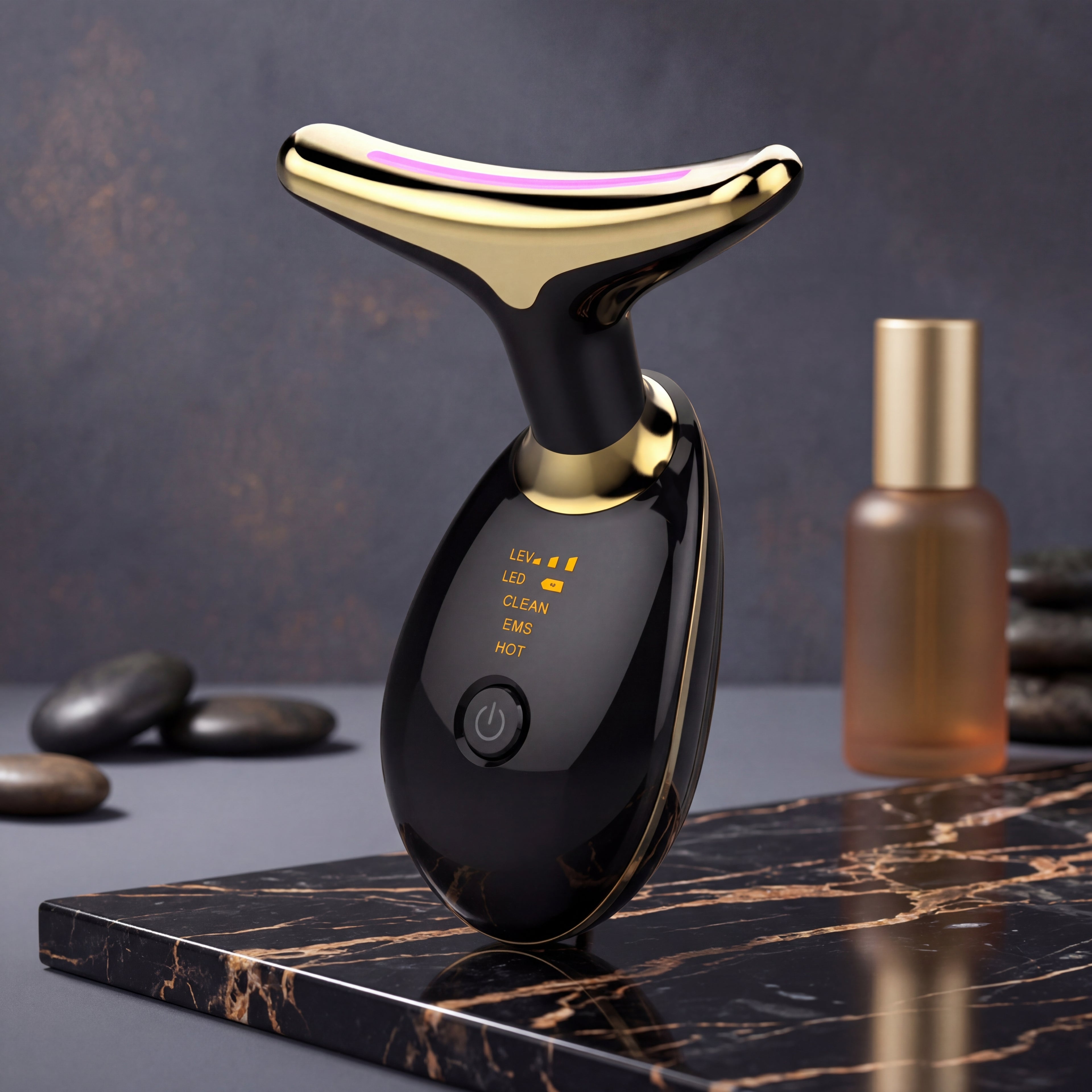 Black and gold electronic device on a marble surface with stones and a bottle in the background