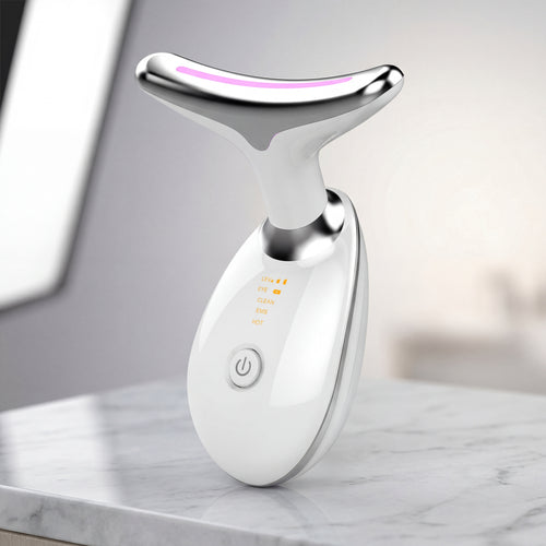 White and silver facial massager on a marble surface with a blurred background