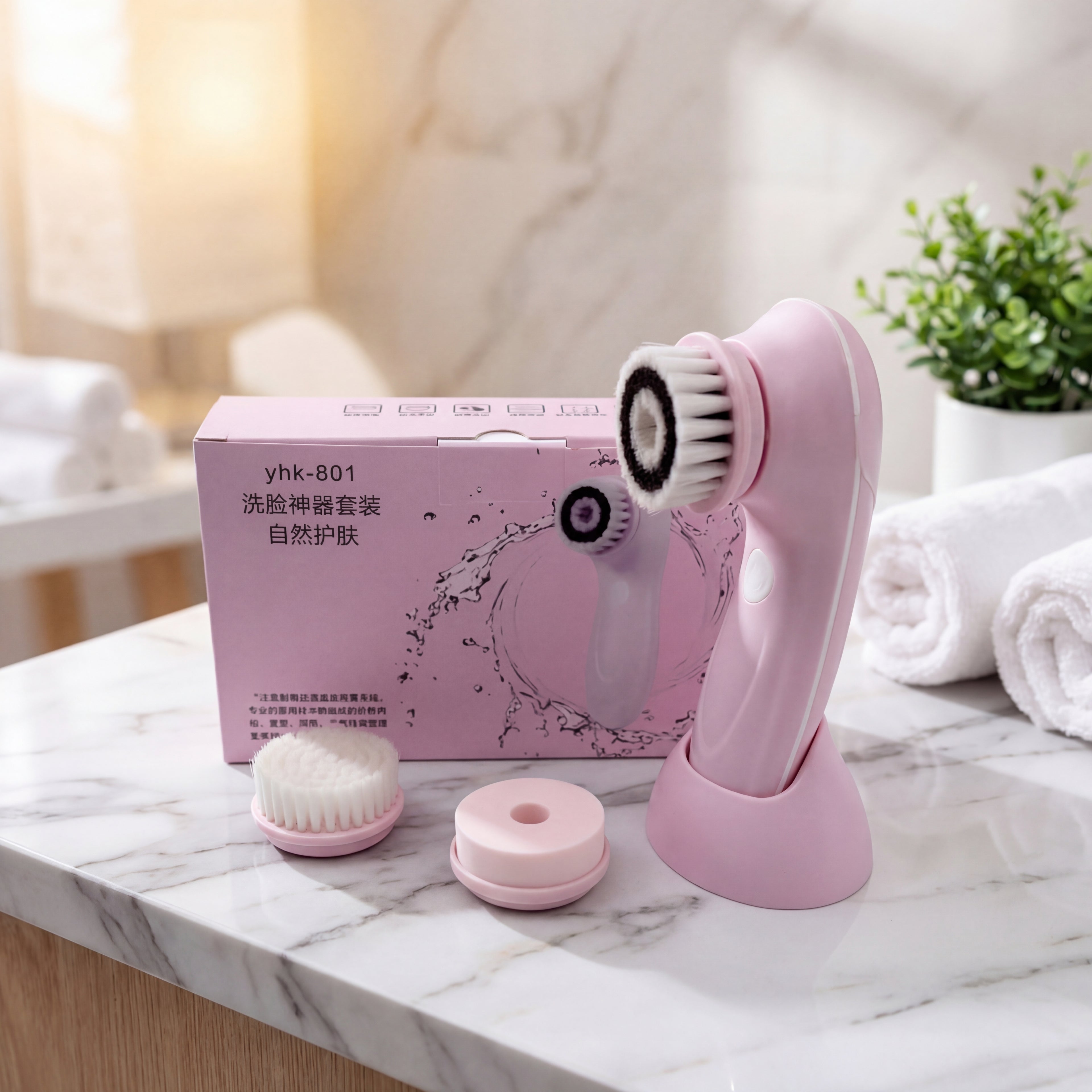 Pink facial cleansing brush set with packaging on a marble surface