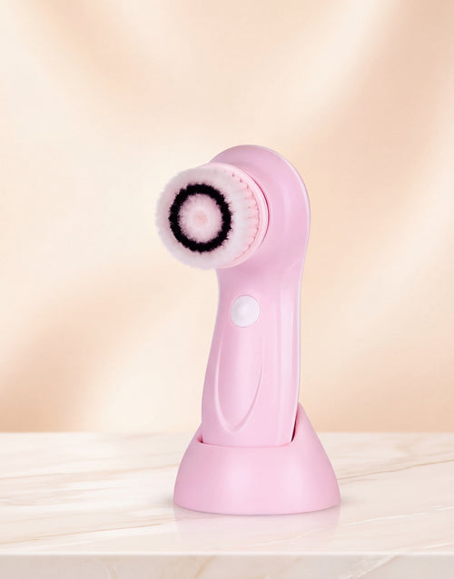Pink facial cleansing brush on a light pink background