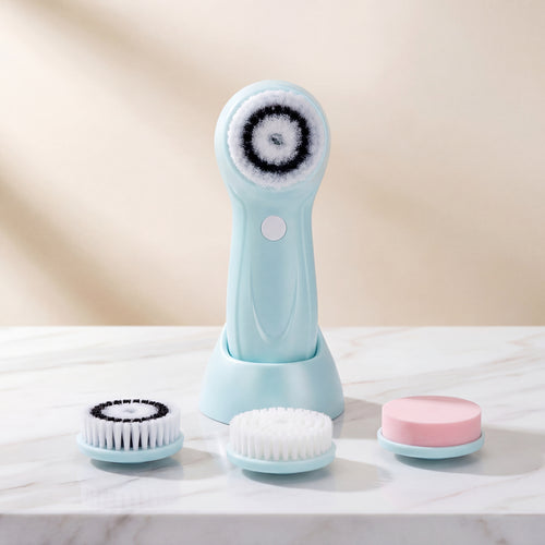 Blue facial cleansing brush with attachments on a marble surface