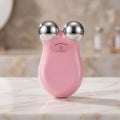 Pink facial massager with silver knobs on a marble surface